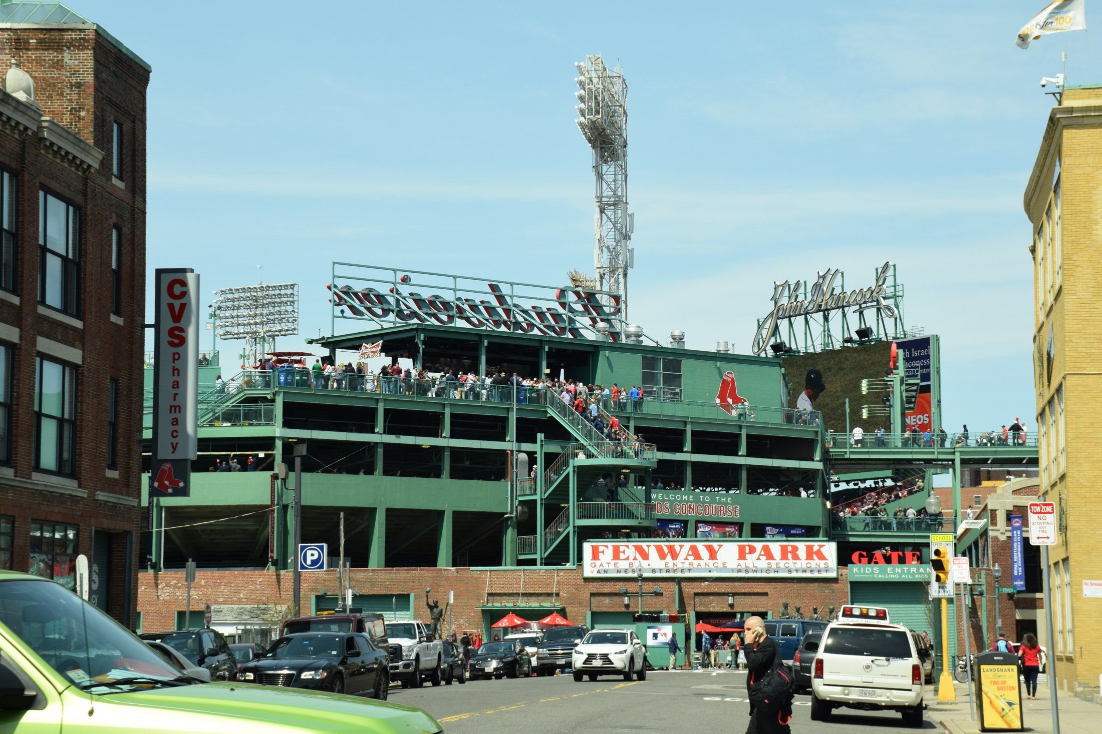 Fenway Park’s green exterior stands and entrance sign above a busy Boston street.