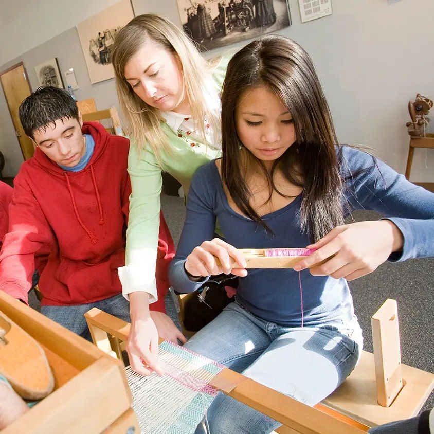 Students and an instructor learning to weave at the Tsongas Industrial History Center in Lowell.
